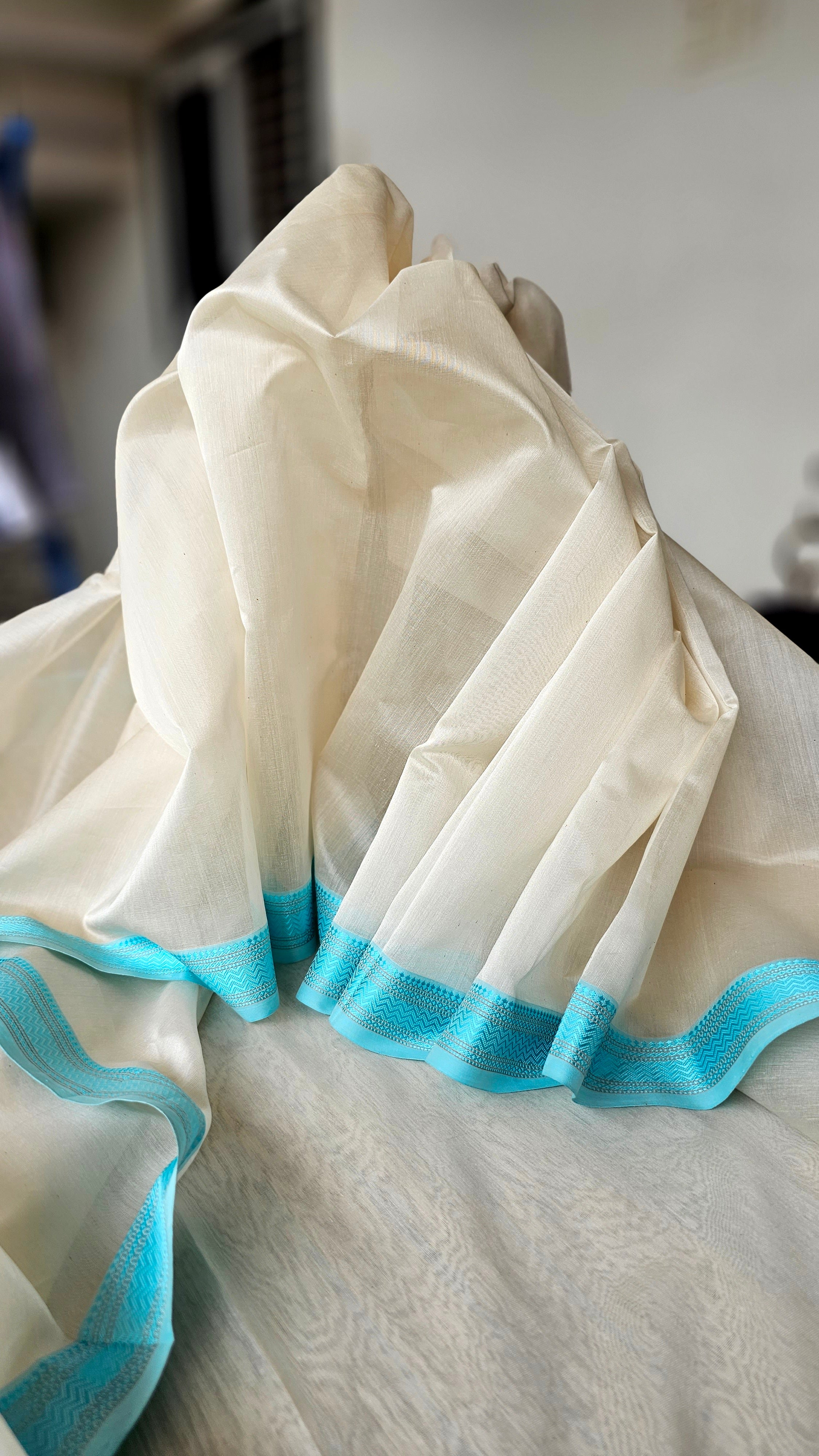 An Off White Saree with Turquoise Blue Resham Borders.