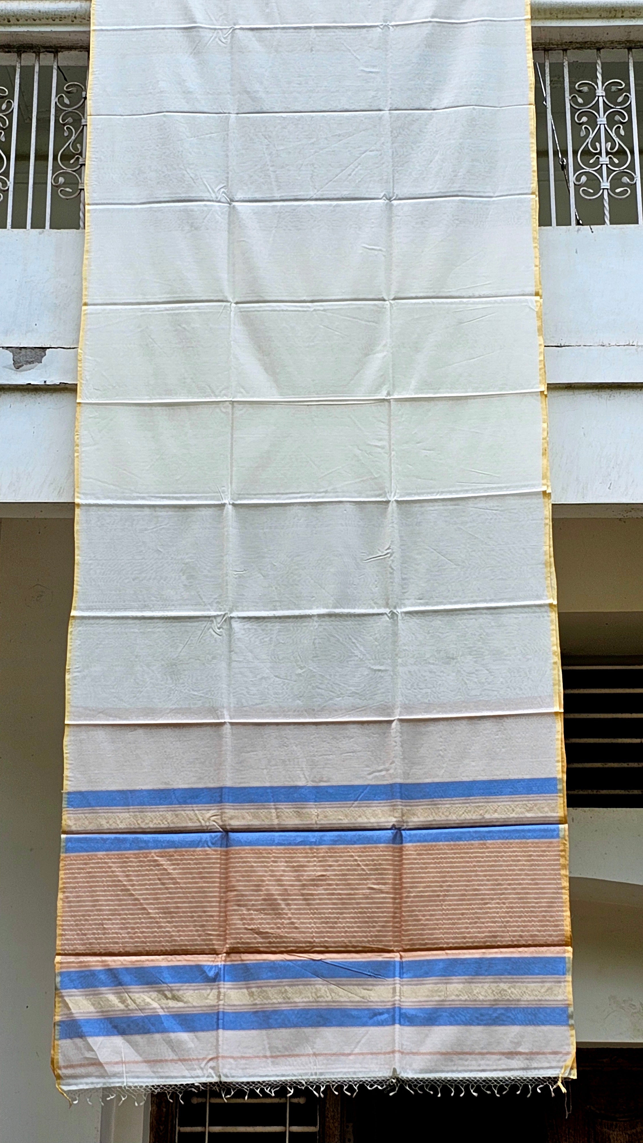 An Off White Saree with Multicolor Pallu and Pale Yellow Selvedges.